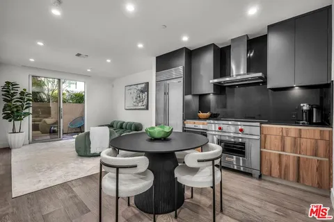 a kitchen with stainless steel appliances granite countertop a stove a refrigerator a sink a dining table and chairs