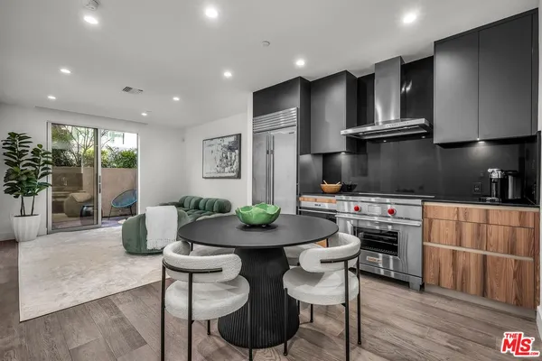 a kitchen with stainless steel appliances granite countertop a stove a refrigerator a sink a dining table and chairs