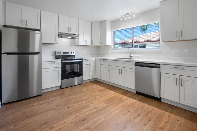 a kitchen with granite countertop a refrigerator stove top oven and sink