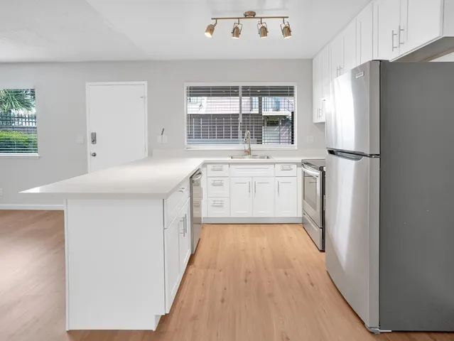a kitchen with a refrigerator a sink and dishwasher with wooden floor