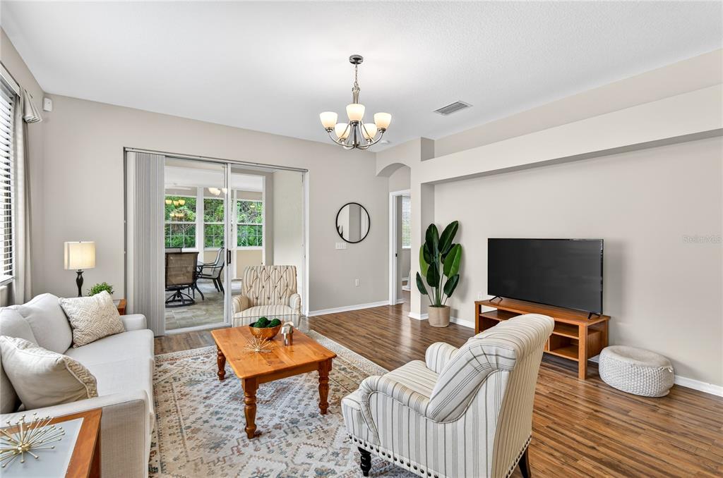 1737 Sassafras Drive Wesley Chapel, FL 33543 - Photo 17 of 58 a living room with furniture a chandelier and a flat screen tv