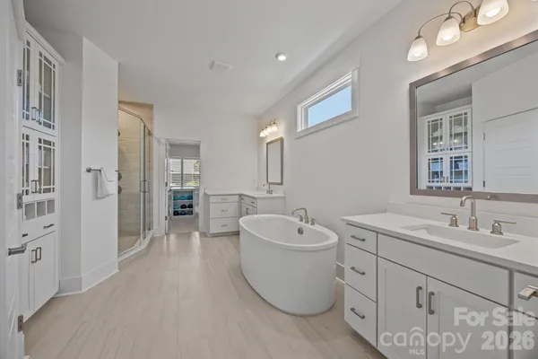 a spacious bathroom with a double vanity sink mirror and bathtub