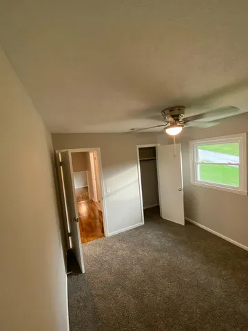 an empty room with closet and a chandelier fan