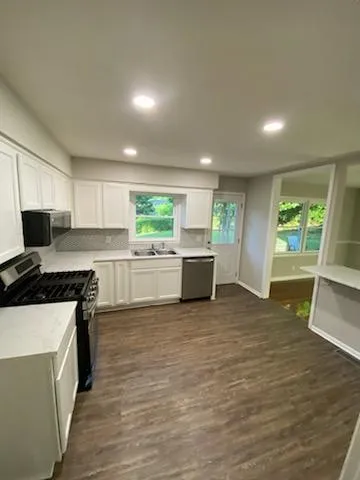 a kitchen with a sink a stove cabinets and wooden floor