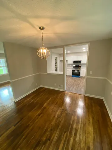 a view of a room with wooden floor staircase and a kitchen