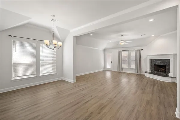 an empty room with wooden floor fireplace and window