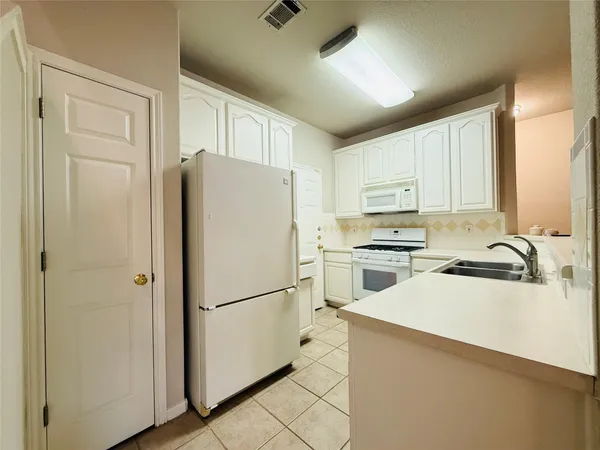 a kitchen with white cabinets and white appliances