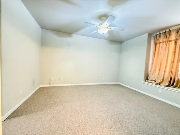 an empty room with windows and chandelier fan