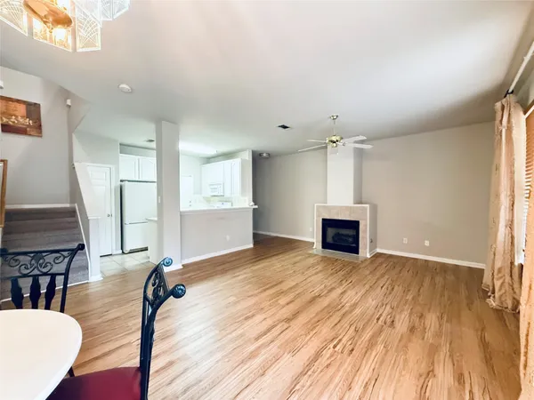 a view of a livingroom with a fireplace a ceiling fan and wooden floor
