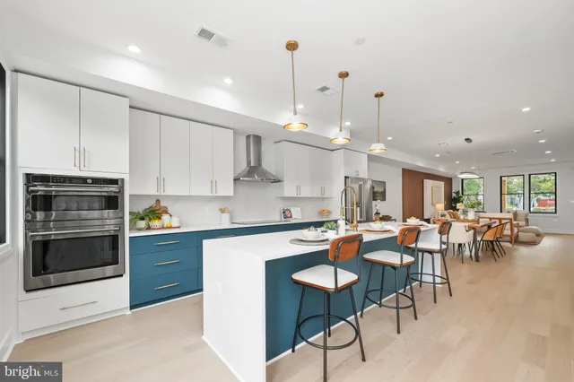 a kitchen with stainless steel appliances kitchen island granite countertop a stove top oven a sink a dining table and chairs with white cabinets