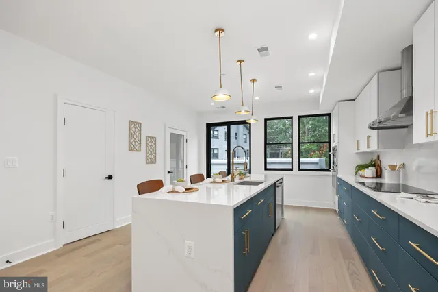 a large kitchen with kitchen island a large counter top space a sink stainless steel appliances and cabinets