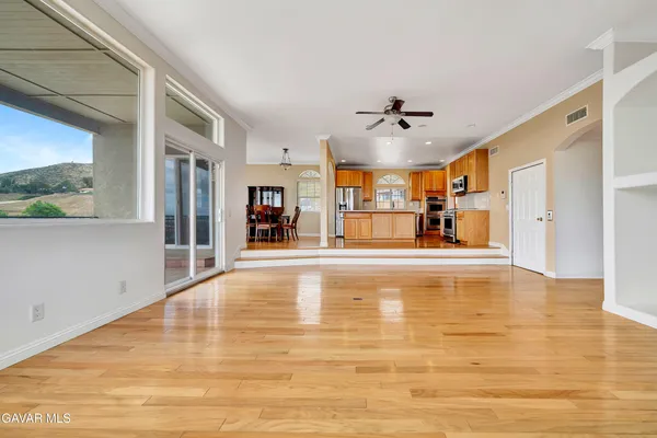 a dining room with wooden floor a chandelier a glass table and chairs