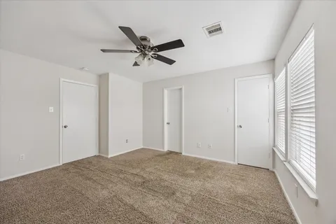 a view of a big room with a ceiling fan and windows
