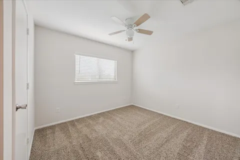 an empty room with a window and a fan
