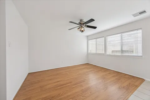 a view of empty room with wooden floor and fan