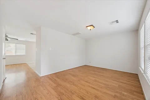 a view of empty room with wooden floor and fan