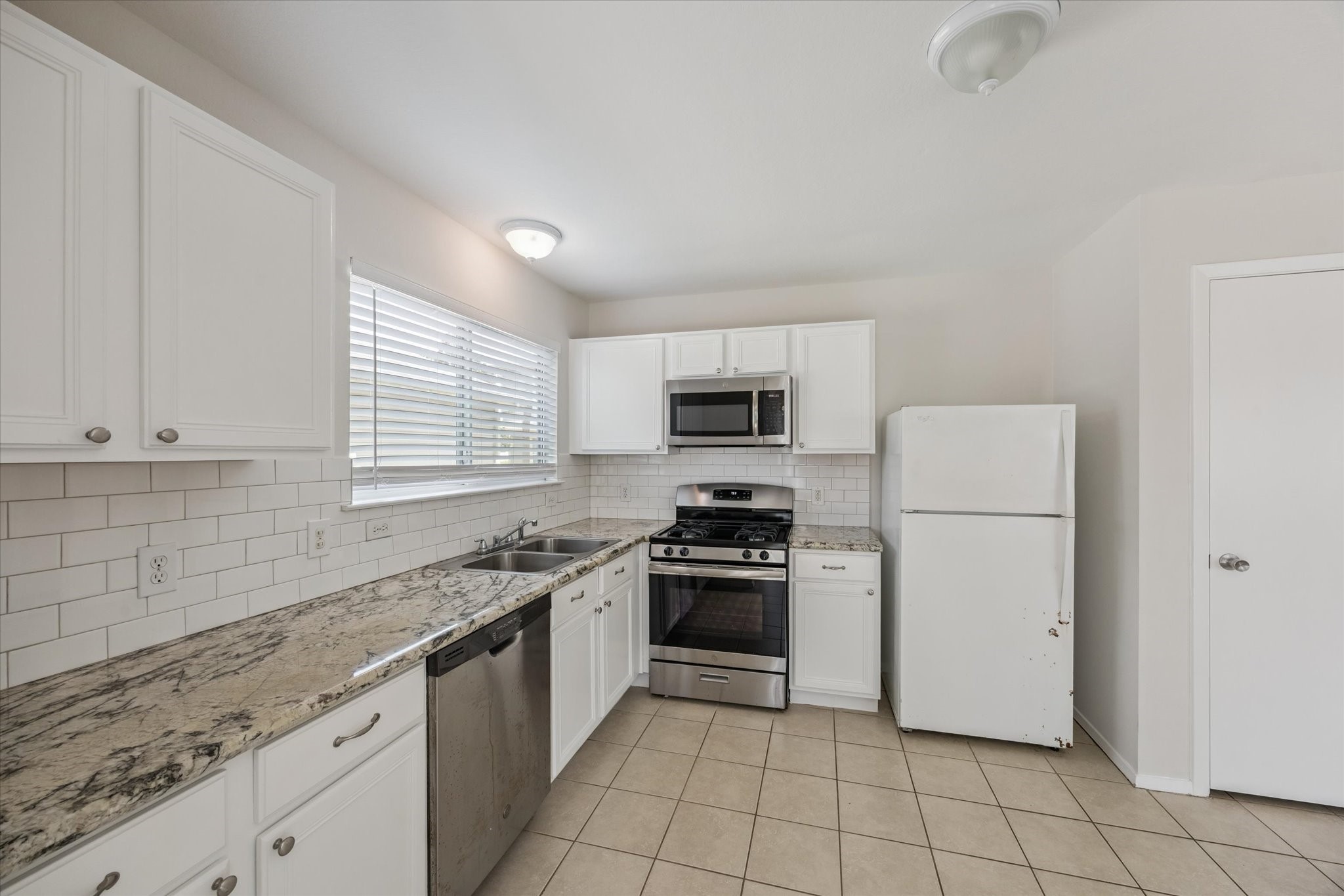 6205 Lone Prairie Way Katy, TX 77449 - Photo 10 of 21 a kitchen with a stove a sink and a refrigerator