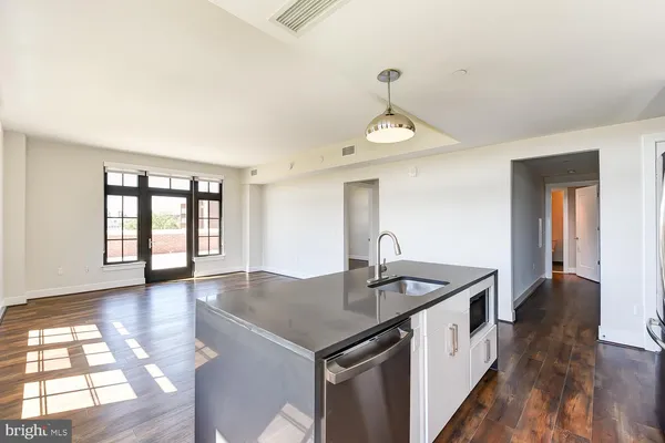 a view of empty room with wooden floor and kitchen view