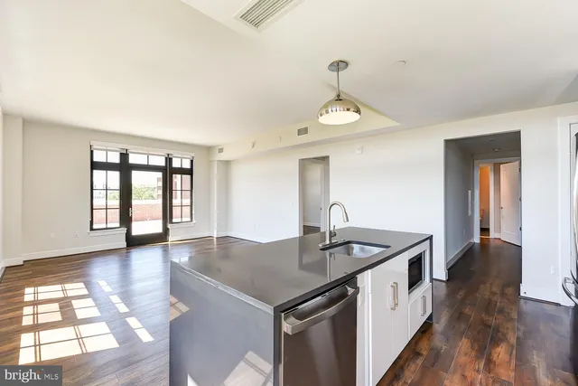 a view of empty room with wooden floor and kitchen view