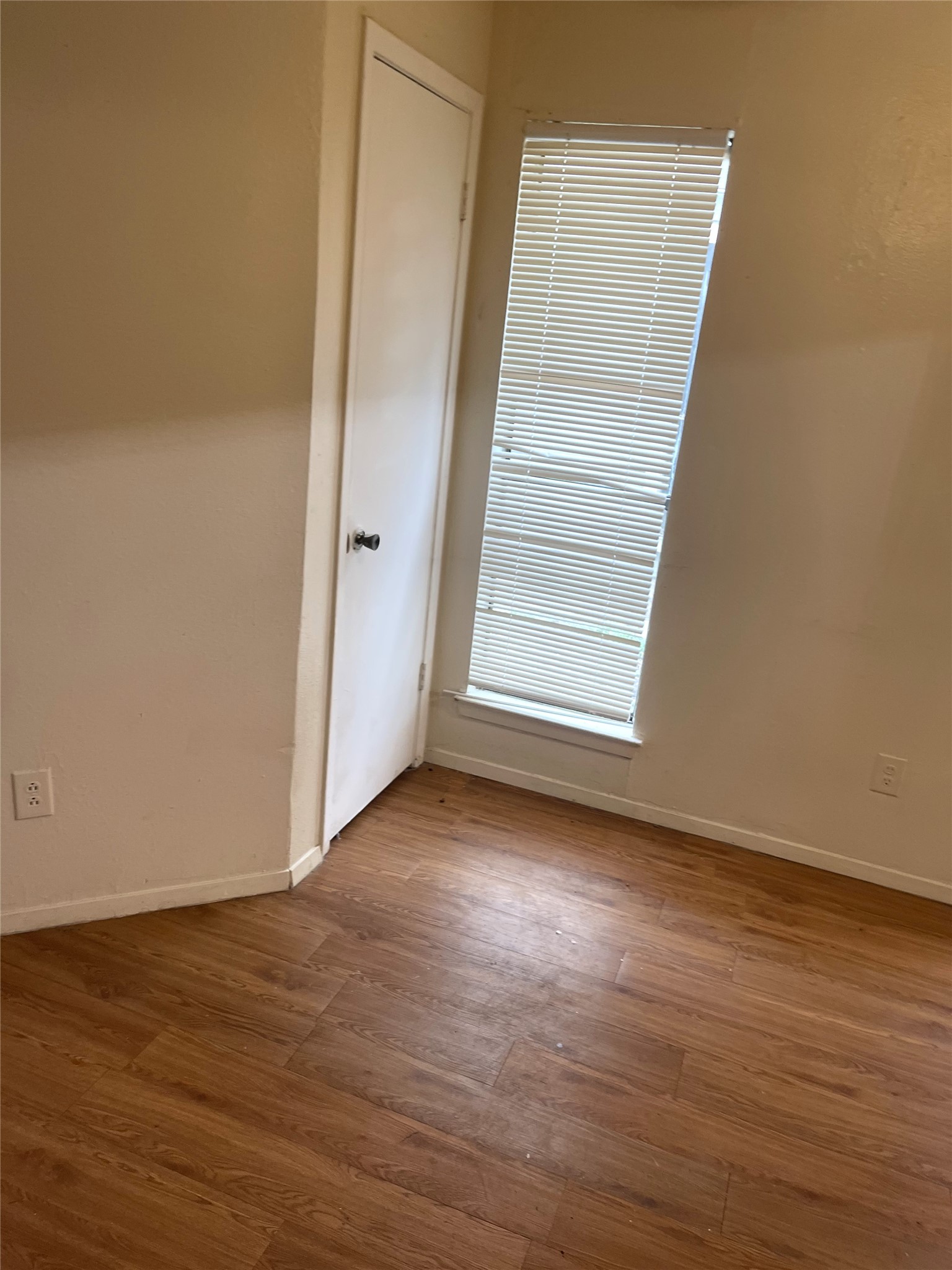 1902 West Loop, Unit B1 Austin, TX 78758 - Photo 12 of 23 Wood-finish flooring throughout, featuring a single window with blinds and a solid paneled door