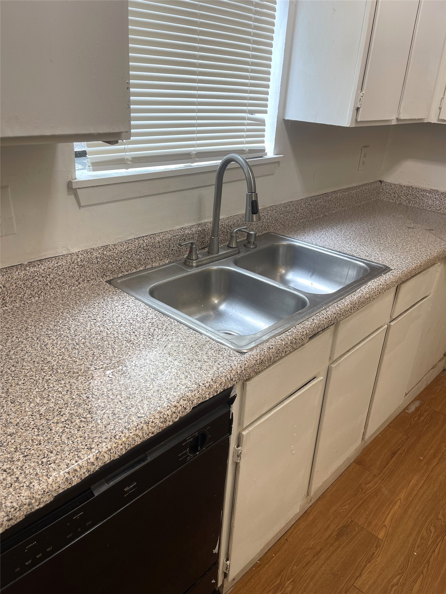 1902 West Loop, Unit B1 Austin, TX 78758 - Photo 16 of 23 Kitchen featuring a stainless steel double basin sink with a high-arch faucet, speckled laminate countertops, a black built-in dishwasher, and white cabinetry