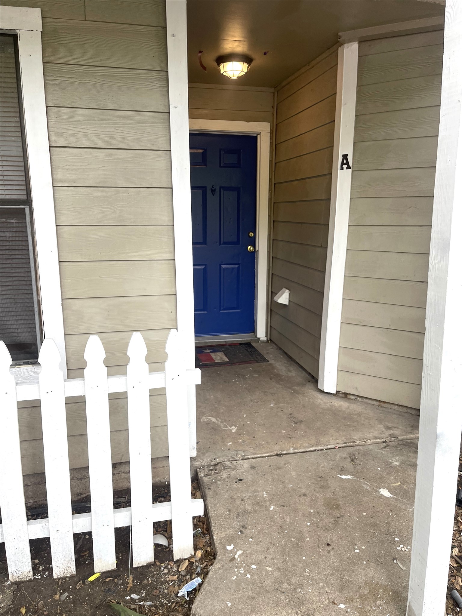 1902 West Loop, Unit B1 Austin, TX 78758 - Photo 18 of 23 Entryway featuring a vibrant blue door, overhead lighting fixture, and durable siding