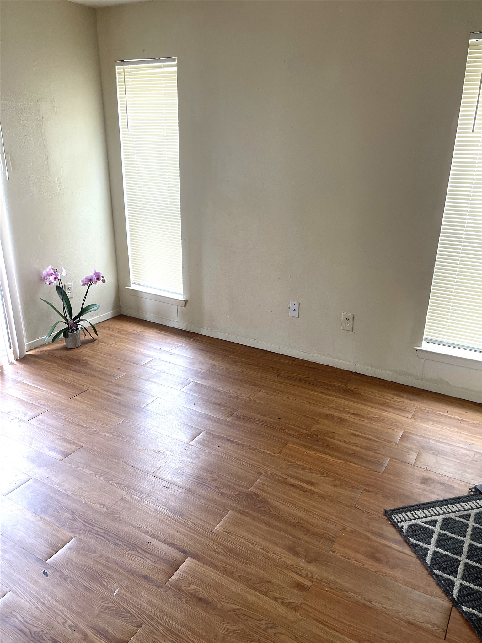 1902 West Loop, Unit B1 Austin, TX 78758 - Photo 8 of 23 Expansive interior room featuring wood-finish flooring, light-colored walls, and multiple windows with blinds