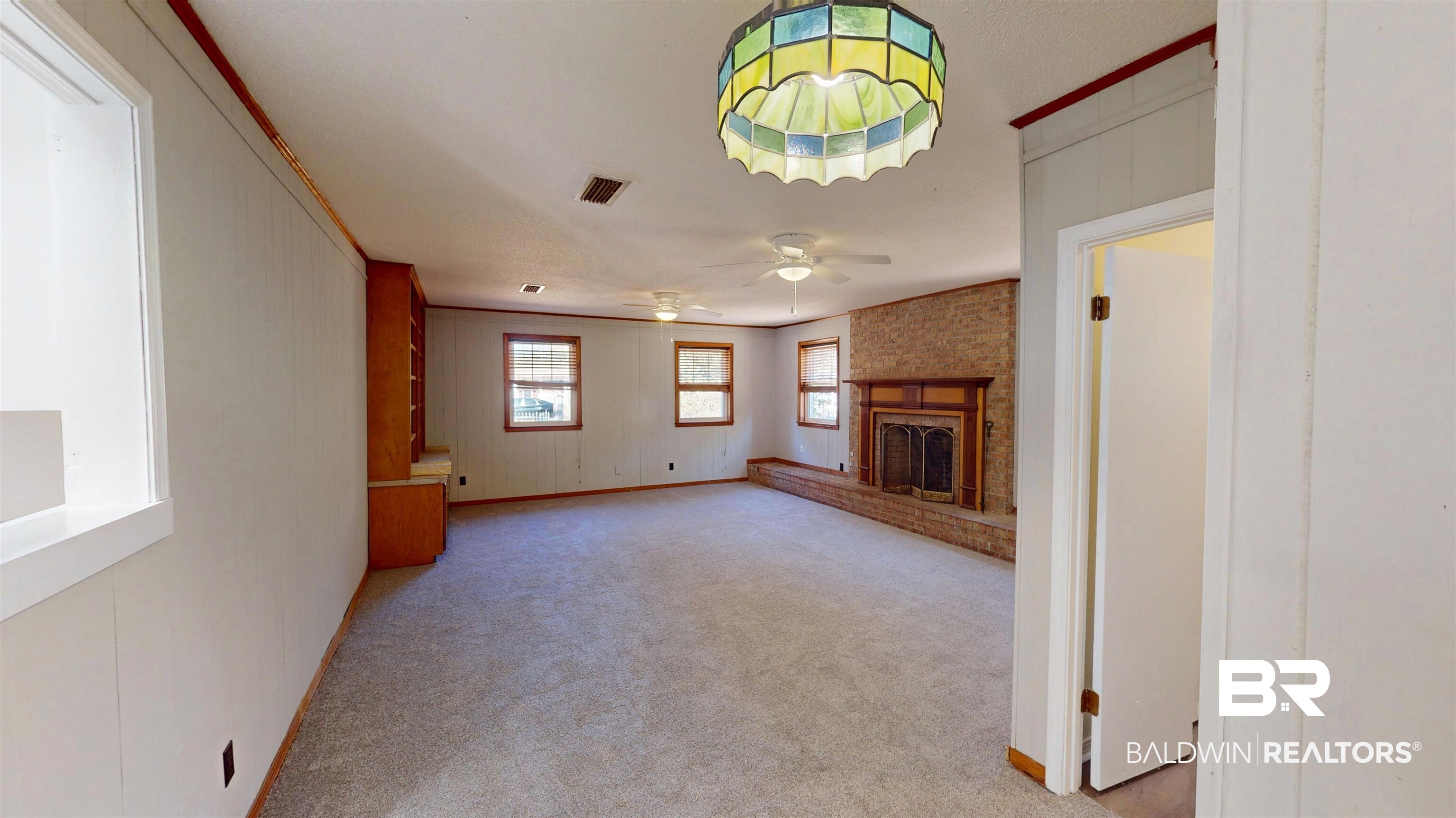 1471 Cedar Crescent Drive Mobile, AL 36605 - Photo 14 of 28 Unfurnished living room with a brick fireplace, light colored carpet, ornamental molding, and a ceiling fan