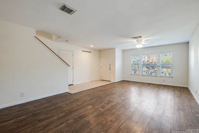 an empty room with wooden floor and windows