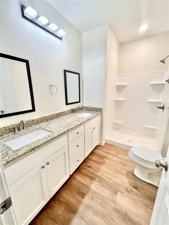 a bathroom with a granite countertop sink toilet and mirror