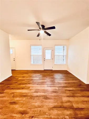 a view of a room with wooden floor and a ceiling fan