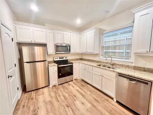 a kitchen with white cabinets stainless steel appliances and window