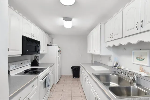 a kitchen with a sink dishwasher a stove and white cabinets with wooden floor