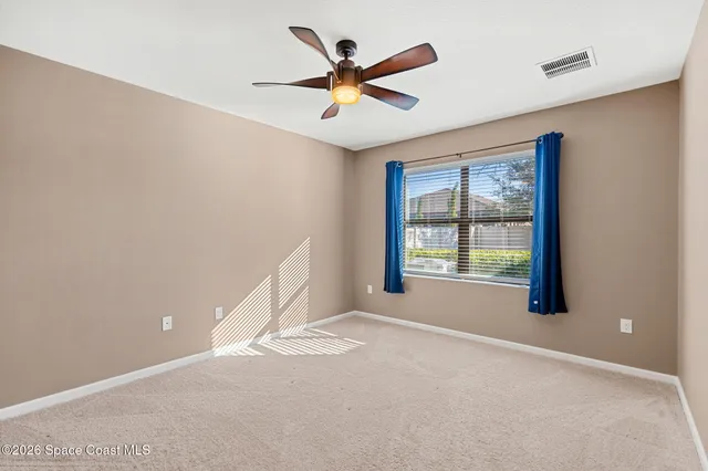 an empty room with a ceiling fan and window