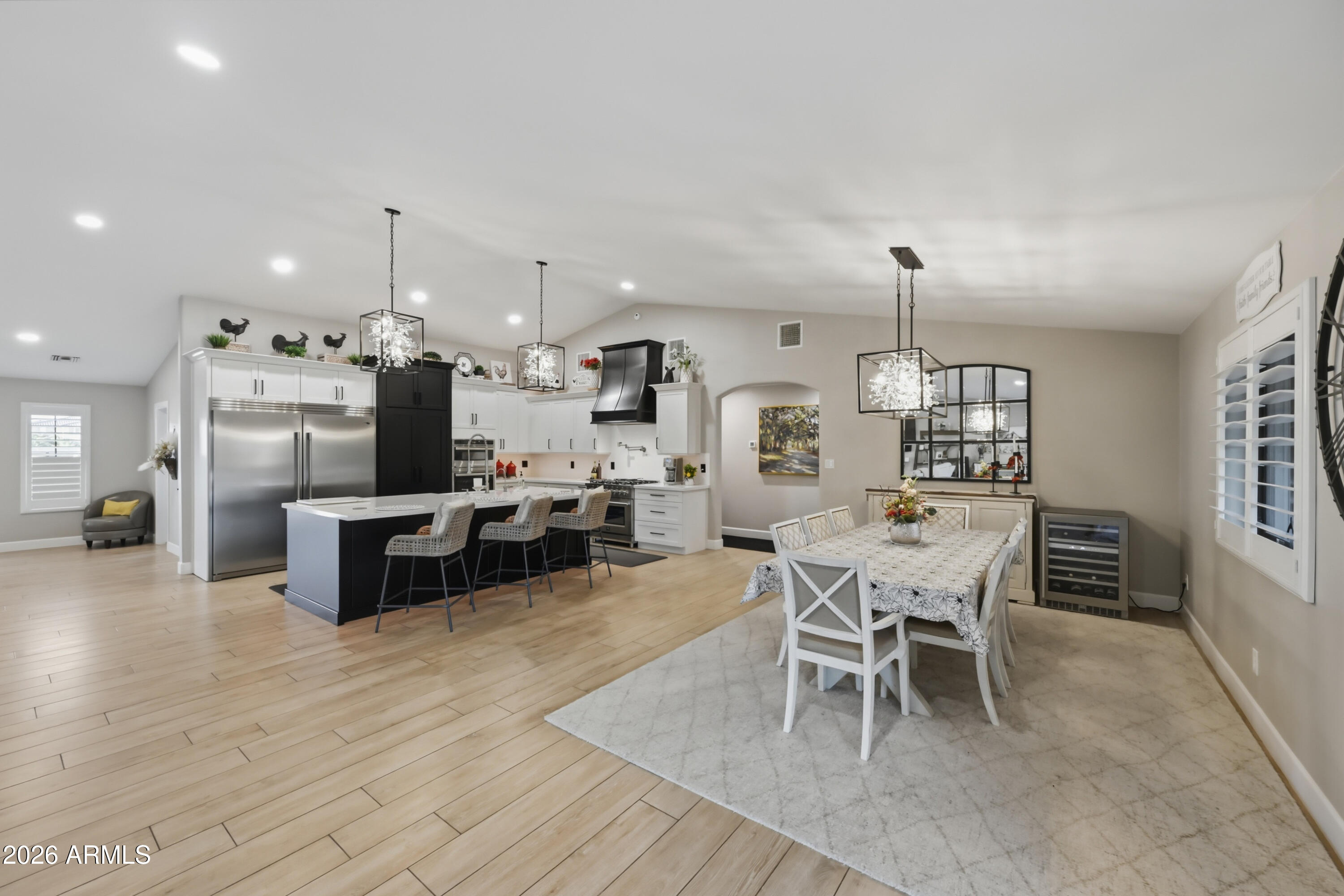 5213 West Dobbins Road Laveen, AZ 85339 - Photo 24 of 69 an open kitchen with stainless steel appliances kitchen island a dining table and chairs with wooden floor