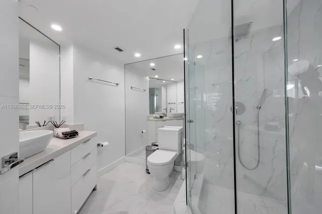 a bathroom with a double vanity sink toilet mirror and shower