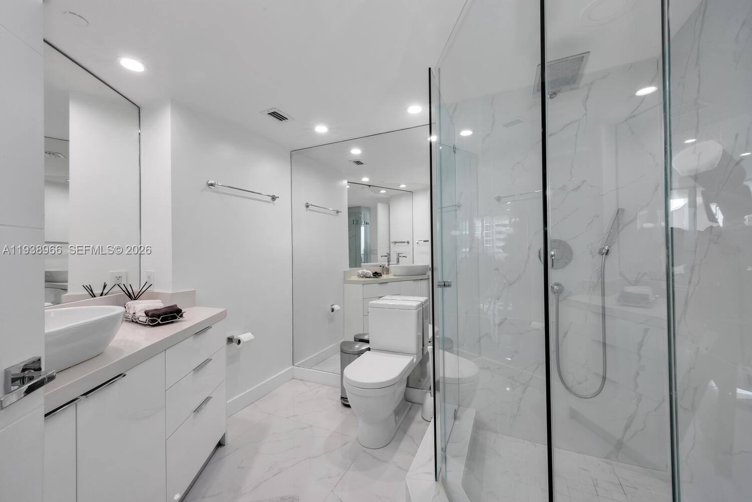 2127 Brickell Avenue, Unit 801 Miami, FL 33129 - Photo 23 of 38 a bathroom with a double vanity sink toilet mirror and shower