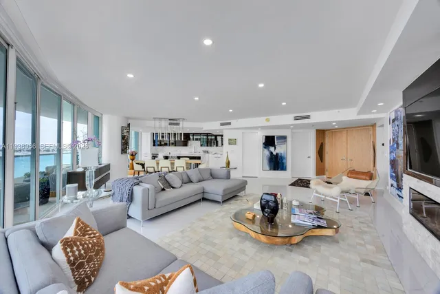 a living room with furniture kitchen view and a large window