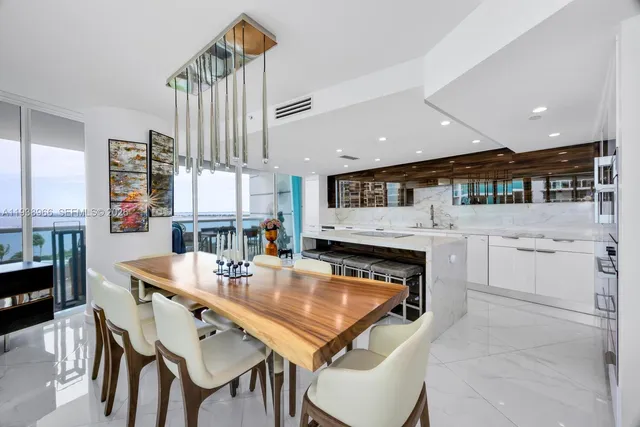 a kitchen with stainless steel appliances kitchen island granite countertop a table chairs and a refrigerator