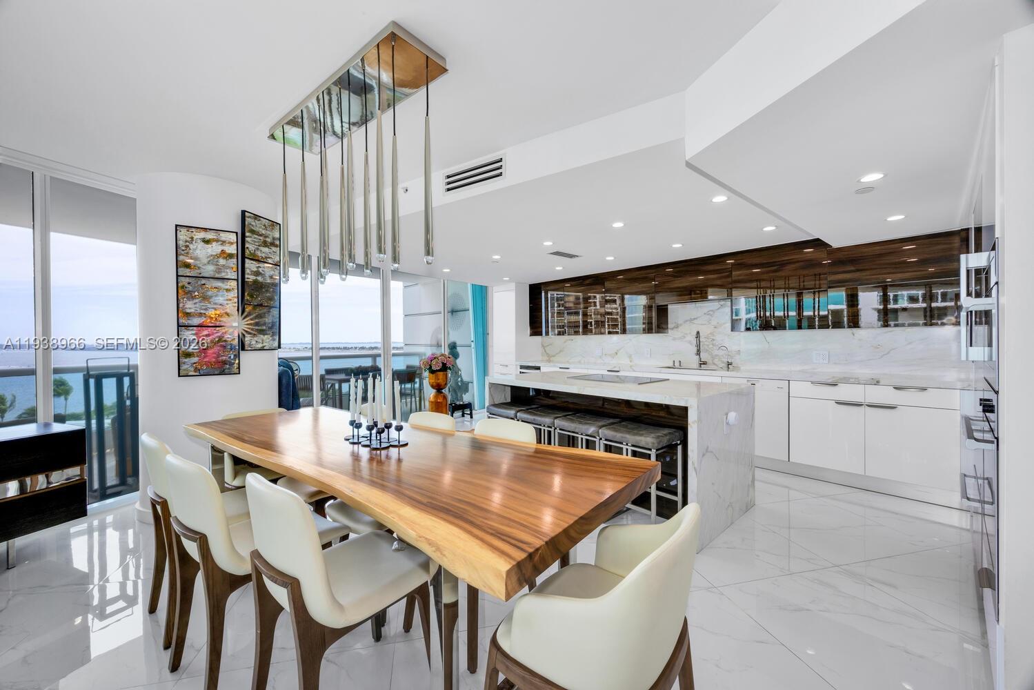 2127 Brickell Avenue, Unit 801 Miami, FL 33129 - Photo 10 of 38 a kitchen with stainless steel appliances kitchen island granite countertop a table chairs and a refrigerator