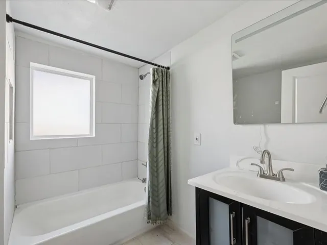 a bathroom with a tub sink vanity and mirror