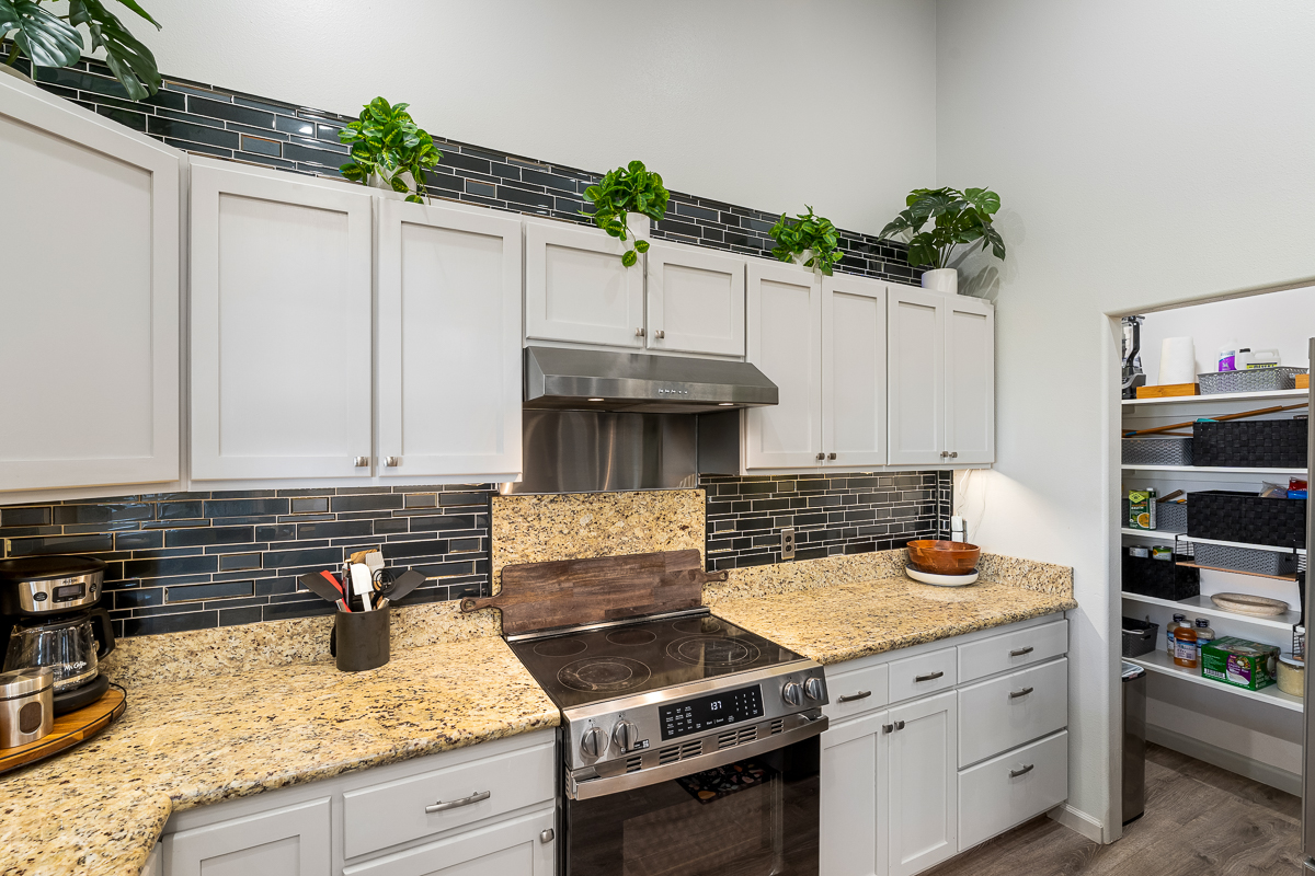 68-1846 Puu Nui Street Waikoloa, HI 96738 - Photo 7 of 29 a kitchen with granite countertop a stove and a white cabinets