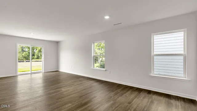 a view of an empty room with wooden floor and window