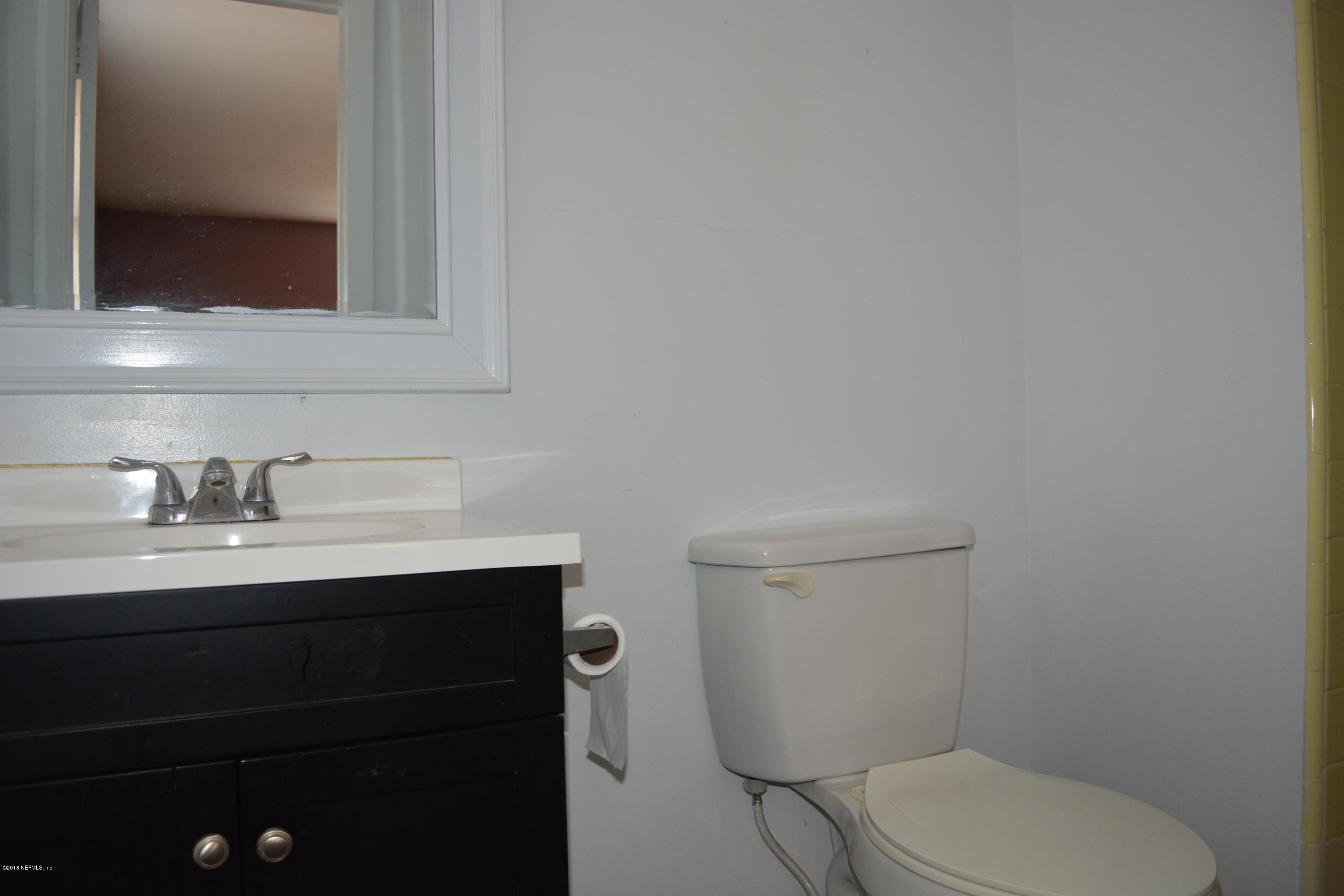 3235 Rogero Road Jacksonville, FL 32277 - Photo 15 of 20 a bathroom with a toilet a sink and mirror