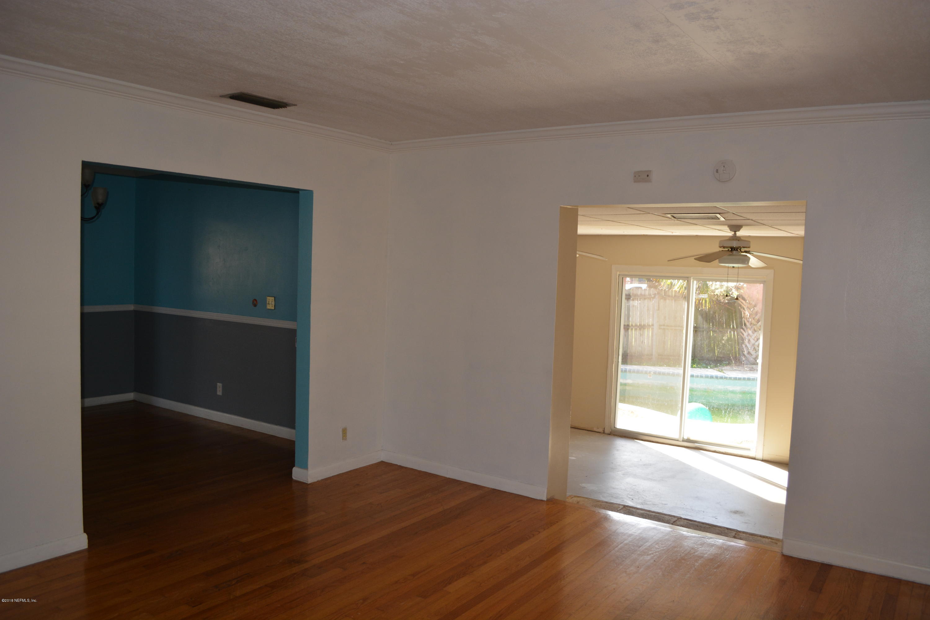 3235 Rogero Road Jacksonville, FL 32277 - Photo 4 of 20 a view of an empty room with wooden floor and a window