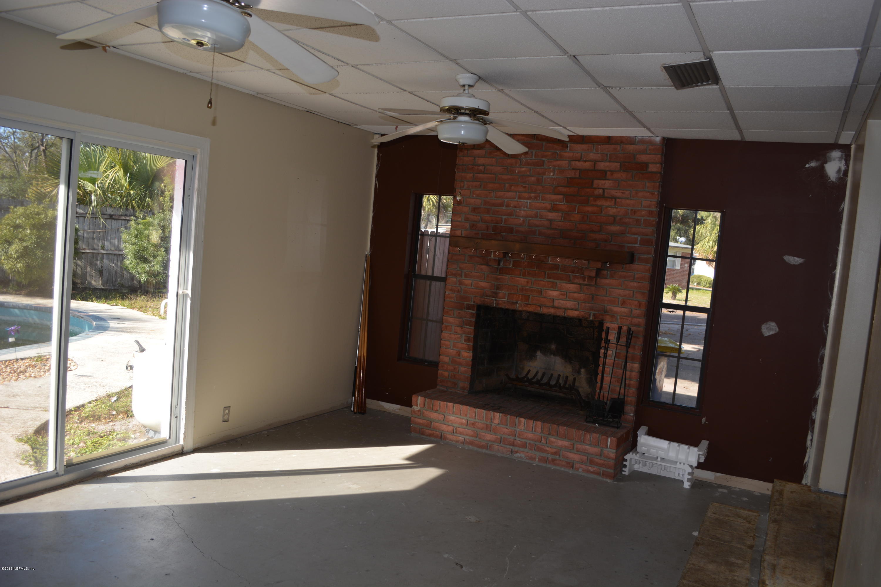 3235 Rogero Road Jacksonville, FL 32277 - Photo 5 of 20 a living room with a fireplace and a flat screen tv