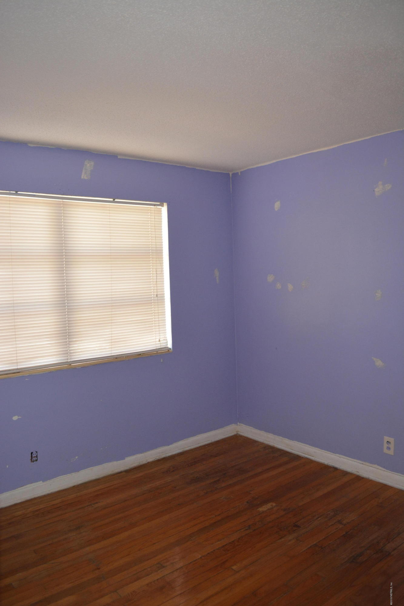 3235 Rogero Road Jacksonville, FL 32277 - Photo 10 of 20 a view of an empty room with wooden floor and a window