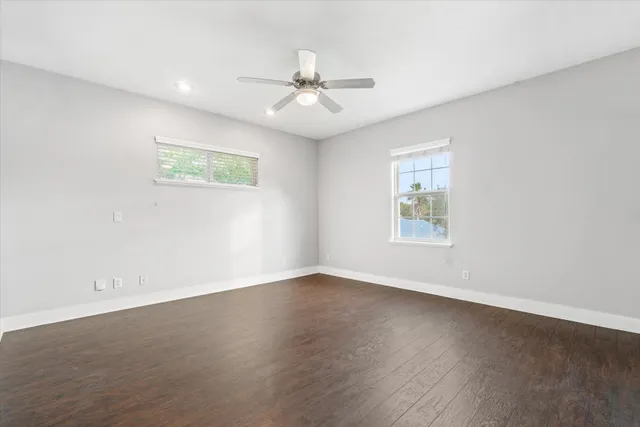 an empty room with wooden floor and ceiling fan