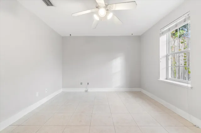 an empty room with windows and fan