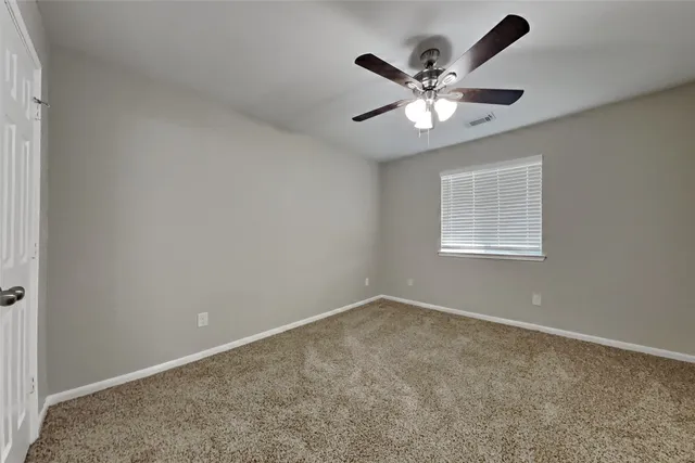 an empty room with a window and a fan